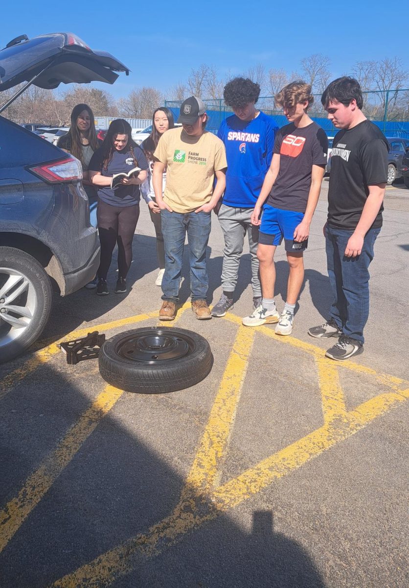 Students in Mr. Bisaccia's spring driver education class learn how to change a tire. 