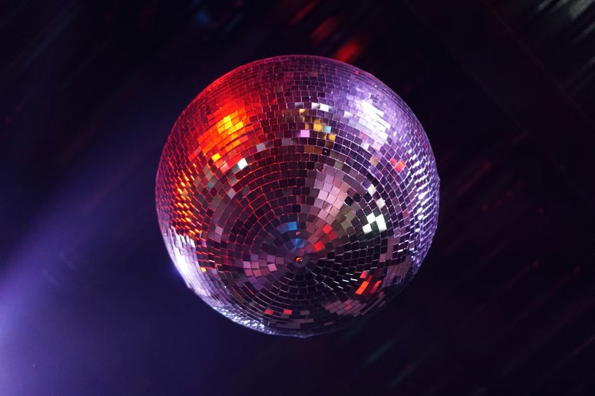 A disco ball reflects bright colored lights. Image courtesy of Unsplash